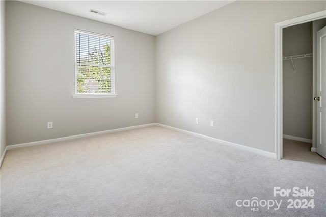 unfurnished bedroom featuring light colored carpet and a closet