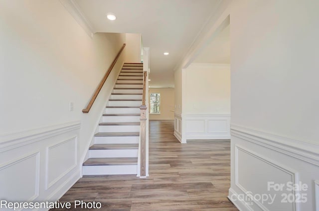 staircase featuring wood-type flooring and ornamental molding