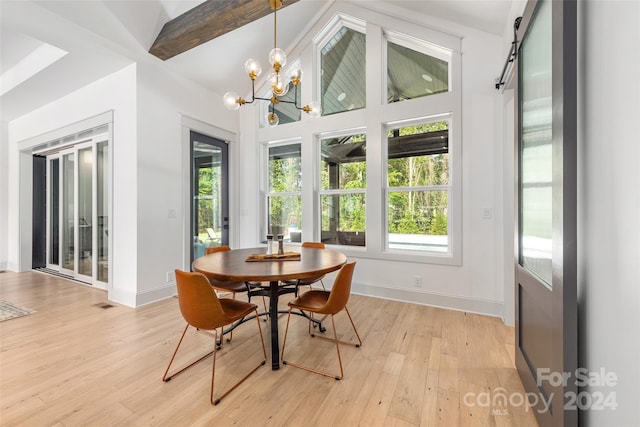 dining space with a barn door, lofted ceiling with beams, light hardwood / wood-style flooring, and a chandelier