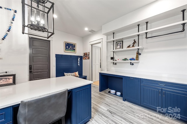 kitchen with pendant lighting, blue cabinetry, and light hardwood / wood-style flooring