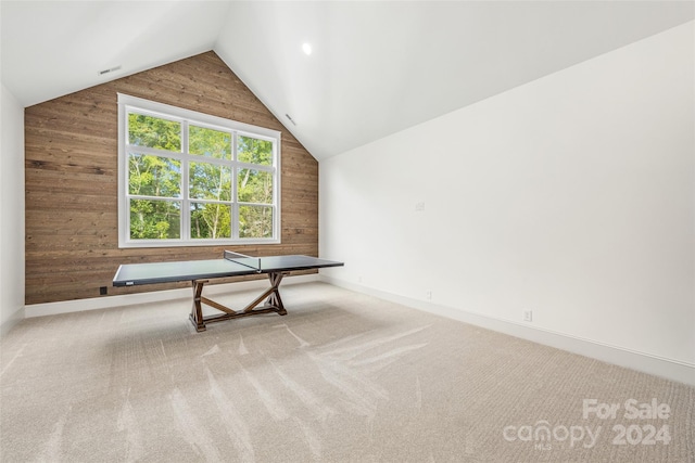 game room with light carpet, wooden walls, and vaulted ceiling