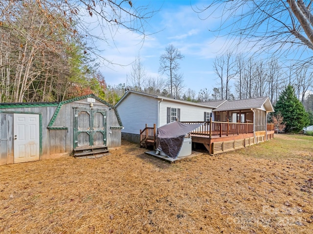 rear view of property with a sunroom, a storage shed, a yard, and a wooden deck