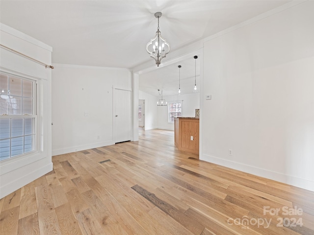 unfurnished living room with a notable chandelier, crown molding, and light hardwood / wood-style flooring