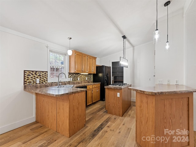 kitchen with kitchen peninsula, backsplash, light hardwood / wood-style floors, and hanging light fixtures