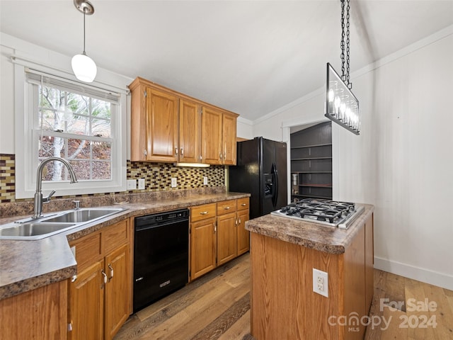 kitchen featuring light wood-type flooring, vaulted ceiling, sink, black appliances, and a center island