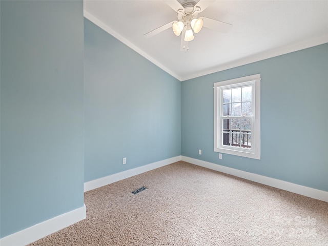 carpeted spare room featuring ceiling fan, vaulted ceiling, and ornamental molding