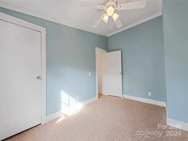 unfurnished bedroom with ceiling fan, light colored carpet, and crown molding