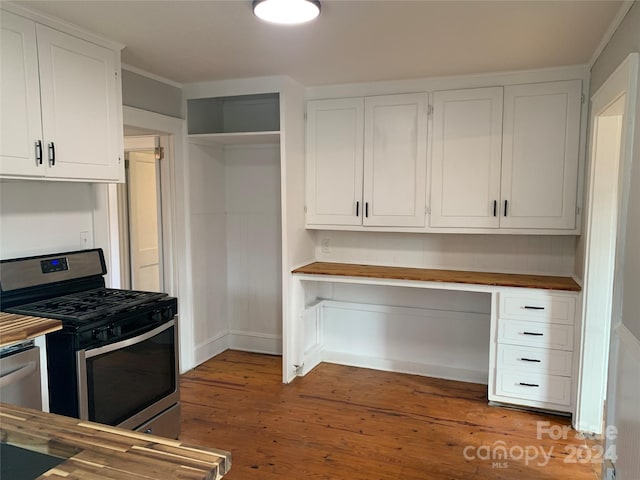 kitchen featuring stainless steel gas range oven, wooden counters, white cabinets, built in desk, and wood-type flooring