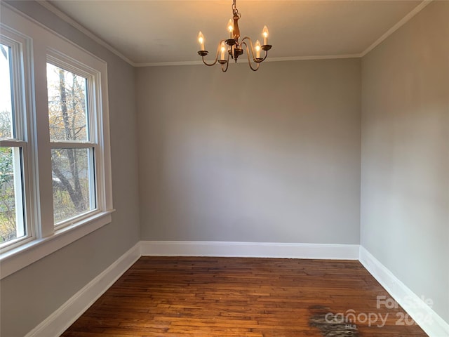 spare room with a notable chandelier, ornamental molding, and dark wood-type flooring