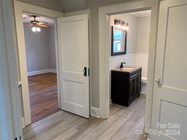 corridor with light hardwood / wood-style flooring and sink