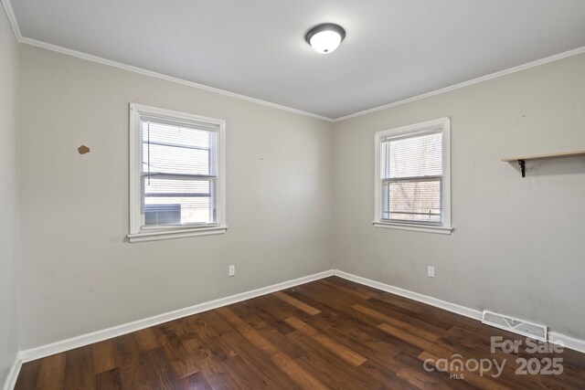 empty room featuring crown molding, baseboards, visible vents, and dark wood-style flooring