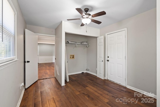 unfurnished bedroom with a closet, ceiling fan, dark wood-type flooring, and baseboards