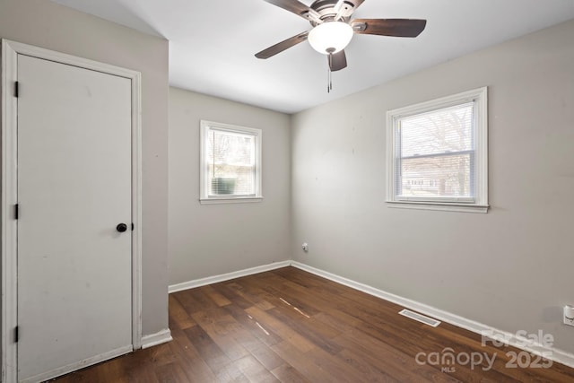 spare room with visible vents, baseboards, dark wood-type flooring, and a ceiling fan