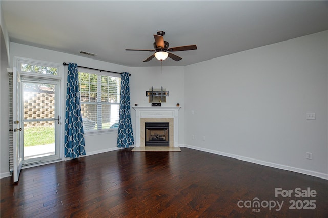 unfurnished living room with dark wood-type flooring, ceiling fan, and a tiled fireplace