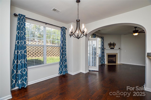 unfurnished dining area with dark hardwood / wood-style flooring and ceiling fan with notable chandelier