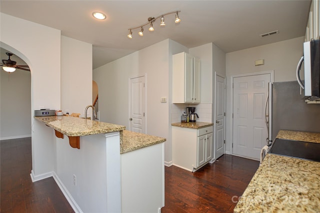 kitchen featuring light stone countertops, appliances with stainless steel finishes, white cabinets, and kitchen peninsula