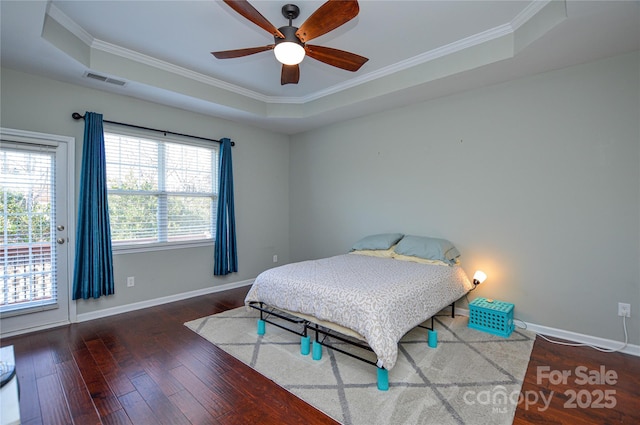 bedroom with ornamental molding, a raised ceiling, and hardwood / wood-style floors