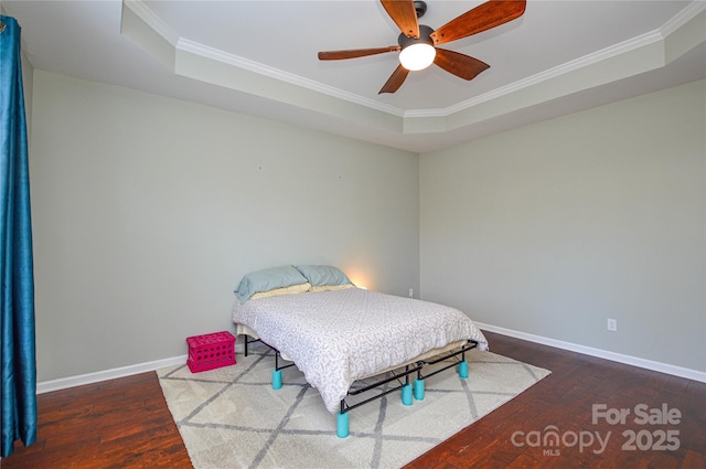 bedroom with crown molding, wood-type flooring, and a tray ceiling