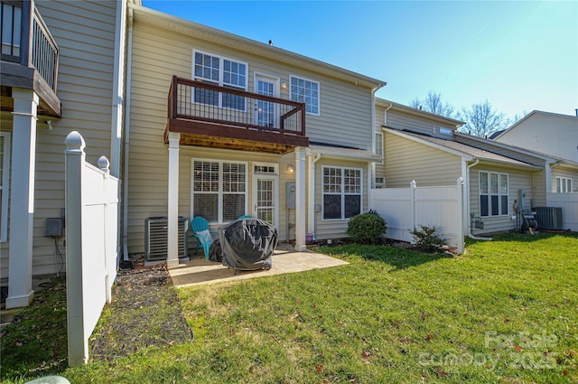 rear view of property featuring central AC unit, a yard, a patio area, and a balcony