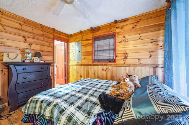 bedroom with hardwood / wood-style floors, a textured ceiling, ceiling fan, and wooden walls