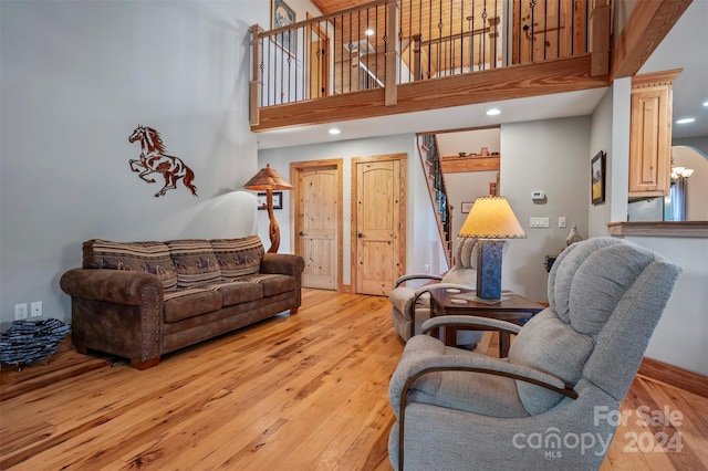 living room with light wood-type flooring and a towering ceiling