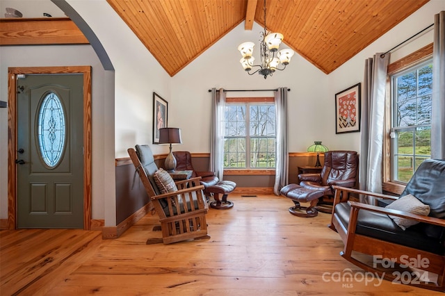 sitting room featuring vaulted ceiling with beams, an inviting chandelier, a wealth of natural light, and light hardwood / wood-style flooring