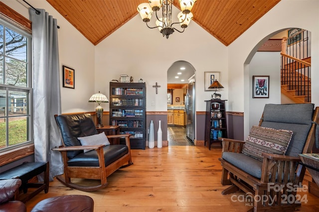 sitting room with high vaulted ceiling, an inviting chandelier, wooden ceiling, and light wood-type flooring