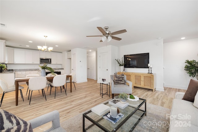 living room with sink, light hardwood / wood-style floors, and ceiling fan with notable chandelier