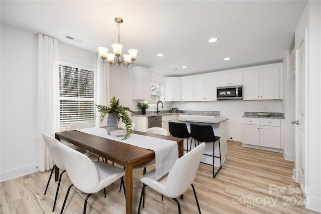 dining space with sink, light hardwood / wood-style flooring, and a notable chandelier