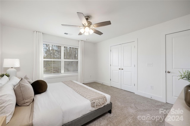 bedroom featuring ceiling fan, light colored carpet, and a closet