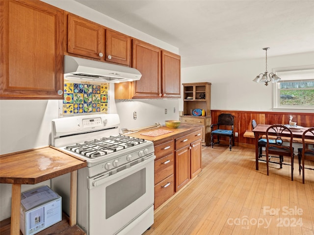 kitchen with wooden counters, white gas range, pendant lighting, an inviting chandelier, and light hardwood / wood-style flooring