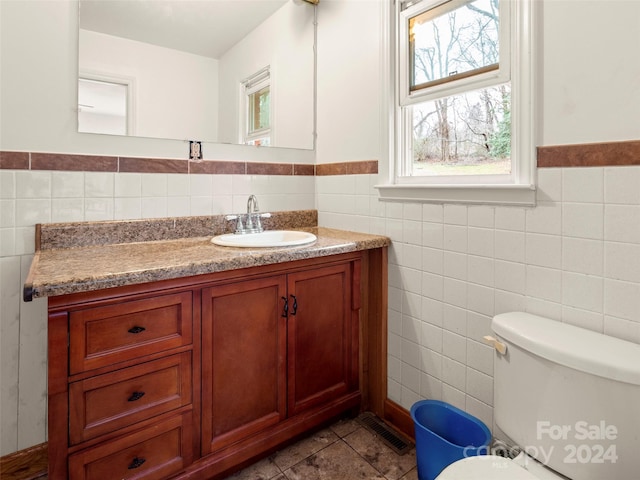 bathroom featuring tile patterned flooring, vanity, toilet, and tile walls