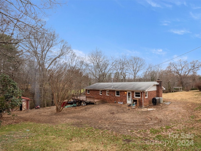 back of property featuring central AC unit, a storage shed, and a wooden deck