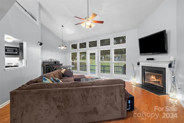 living room with high vaulted ceiling, wood-type flooring, and ceiling fan with notable chandelier