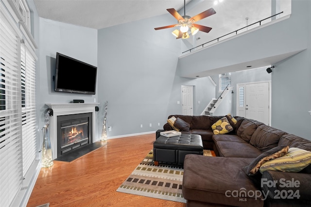 living room with wood-type flooring, a towering ceiling, and ceiling fan