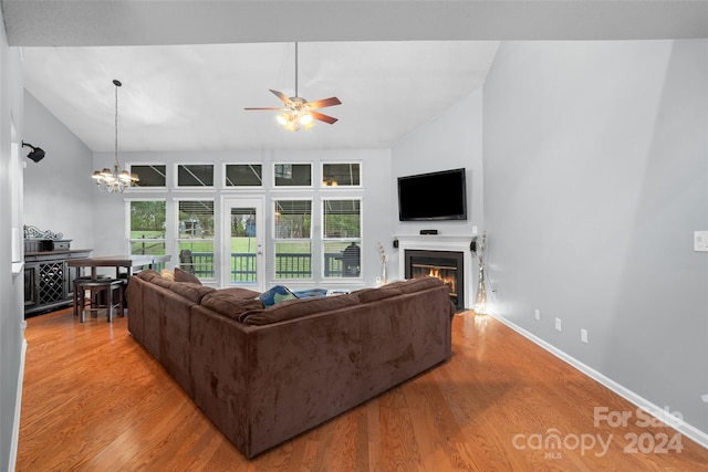 living room with high vaulted ceiling, ceiling fan with notable chandelier, and light wood-type flooring