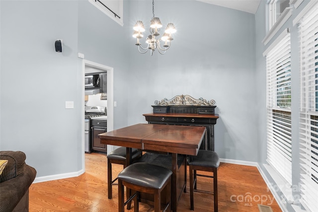 dining room with a notable chandelier, light hardwood / wood-style floors, and a towering ceiling