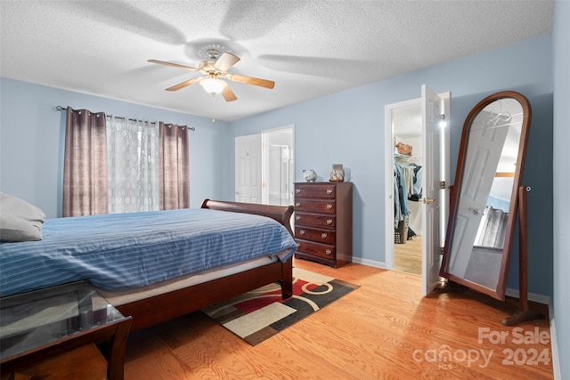 bedroom featuring a closet, ceiling fan, light hardwood / wood-style flooring, and a textured ceiling