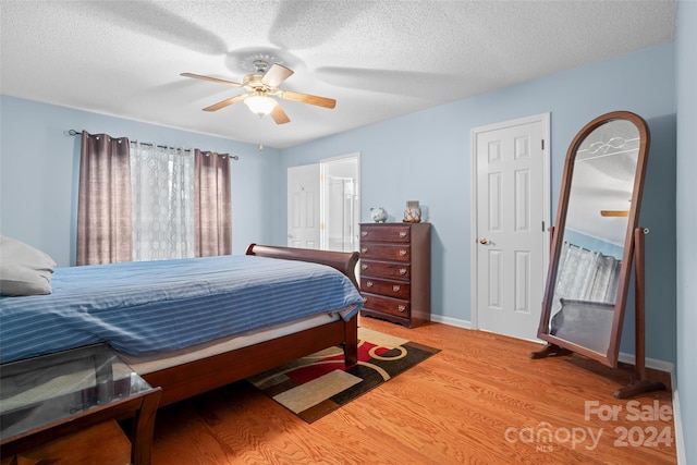 bedroom with ceiling fan, hardwood / wood-style floors, and a textured ceiling