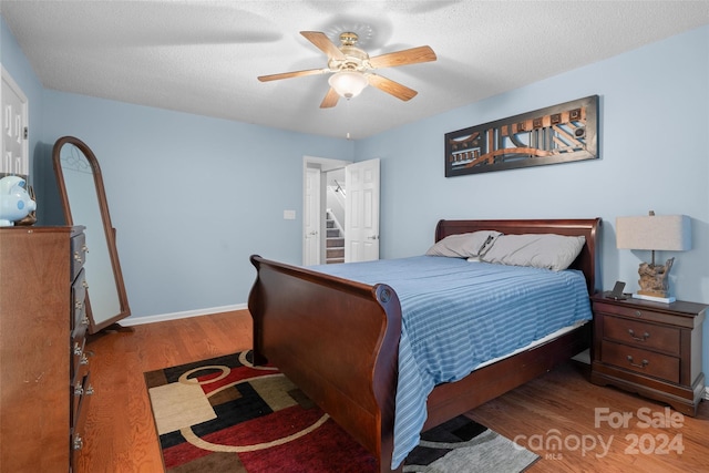 bedroom featuring hardwood / wood-style floors, a textured ceiling, and ceiling fan