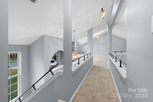 hallway with lofted ceiling with beams, light carpet, and an inviting chandelier