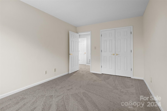 unfurnished bedroom with light colored carpet and a closet