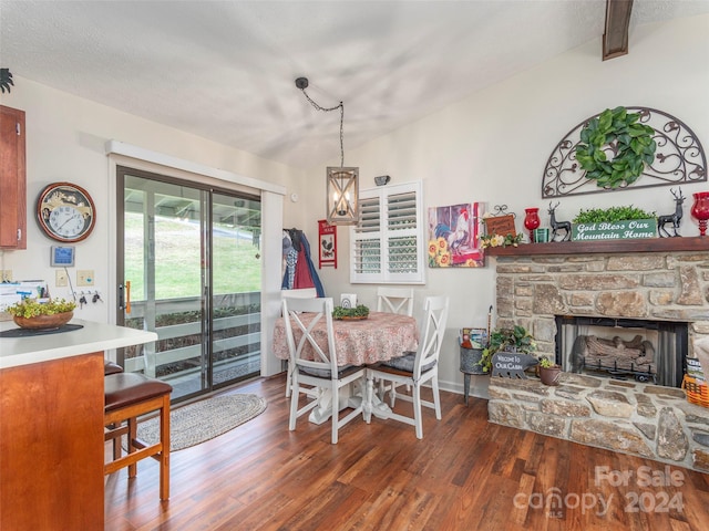 dining room featuring lofted ceiling with beams, a fireplace, dark wood-type flooring, and a textured ceiling