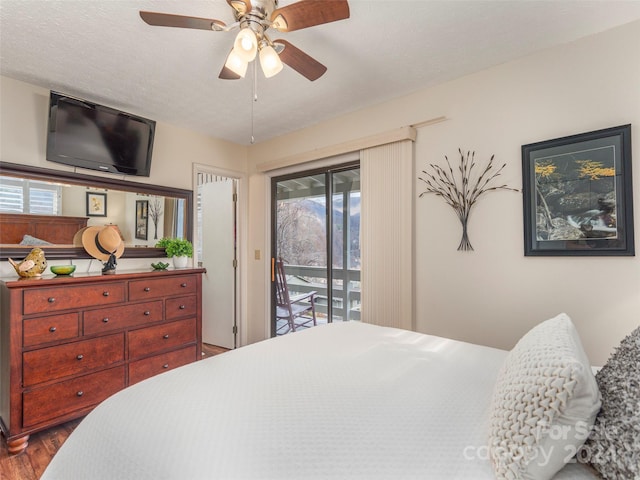 bedroom featuring access to exterior, ceiling fan, hardwood / wood-style floors, and a textured ceiling