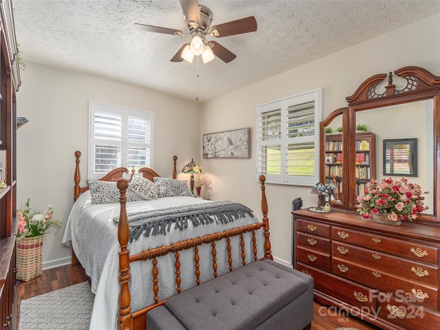 bedroom with ceiling fan, dark wood-type flooring, and a textured ceiling