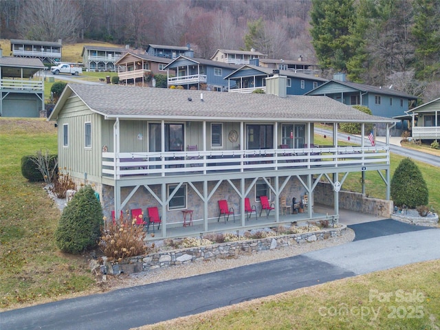 view of front facade with aphalt driveway, stone siding, board and batten siding, and roof with shingles