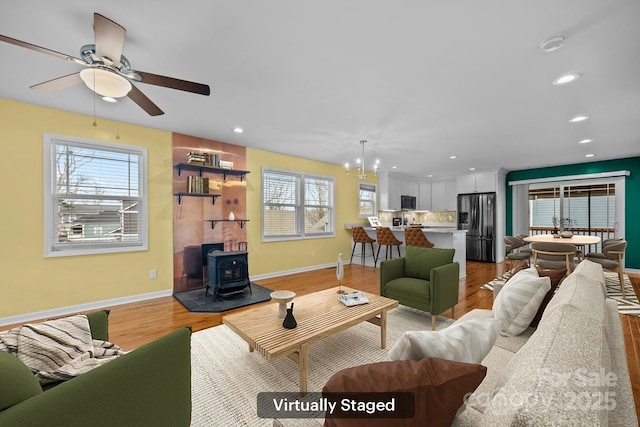 113 Burton St, Asheville, NC 28806 - living area featuring baseboards, recessed lighting, light wood-style floors, ceiling fan with notable chandelier, and a wood stove