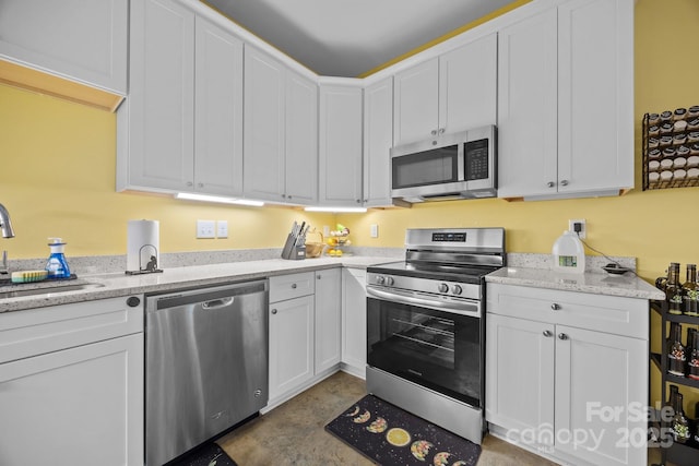113 Burton St, Asheville, NC 28806 - kitchen featuring white cabinets, light stone counters, stainless steel appliances, a sink, and concrete floors