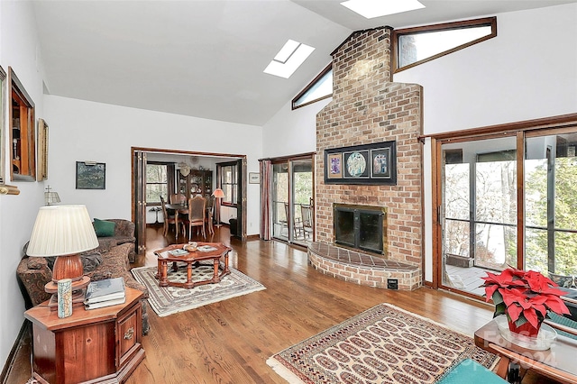 living room with lofted ceiling with skylight, light hardwood / wood-style flooring, and a brick fireplace