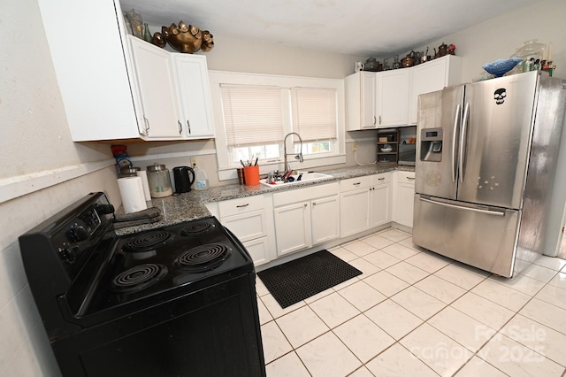 kitchen with light stone countertops, stainless steel refrigerator with ice dispenser, white cabinets, black / electric stove, and light tile patterned flooring